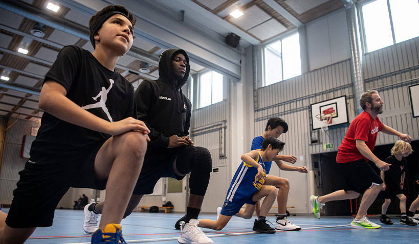 Spelar basket inomhus.
