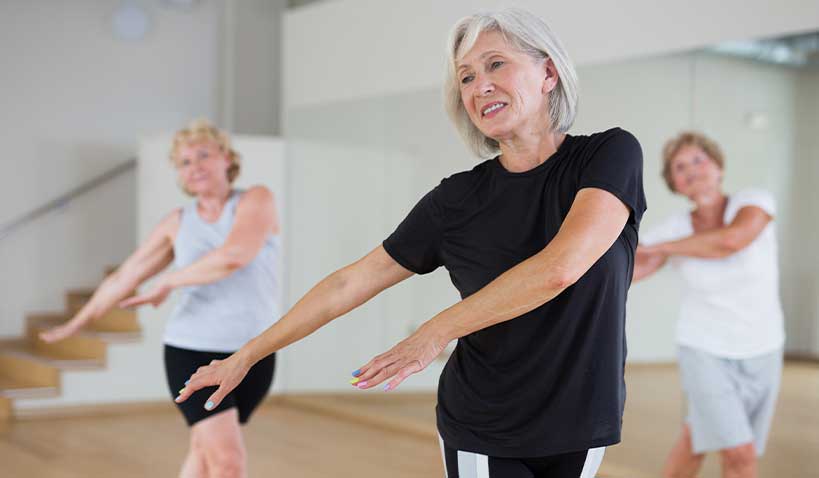 Lycklig äldre dam som dansar i dansklass
