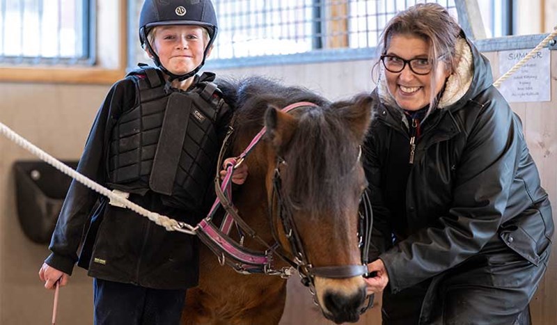 En ponny med två glada hästtjejer
