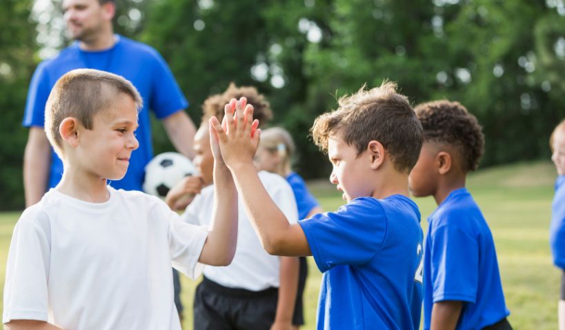 Barn som spelar fotboll och gör high five