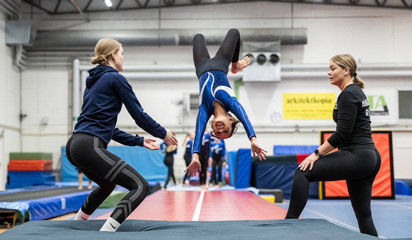 Leende flicka gör bakåtvolt på tjockmatta i Halmstads Gymnastikförening