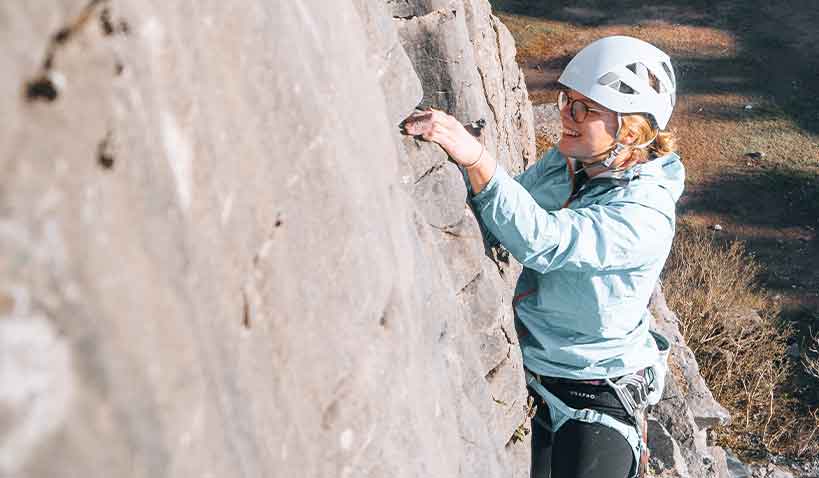 Kvinna klättrar på bergsvägg