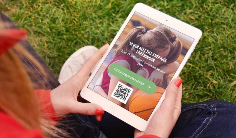 En surfplatta som visar Folkspels hemsida och en QR-kod