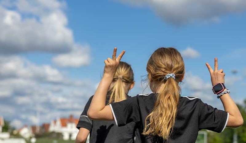 Glad fotbollsspelare gör segertecken mot himmel