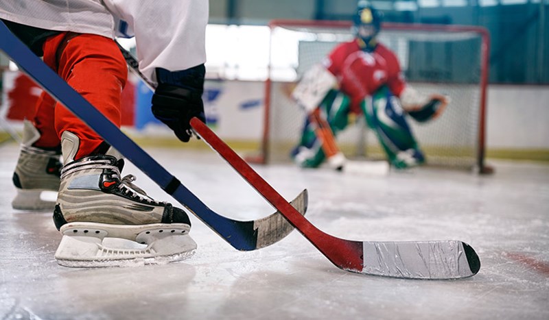 Närbild på skridskor och hockeyklubba