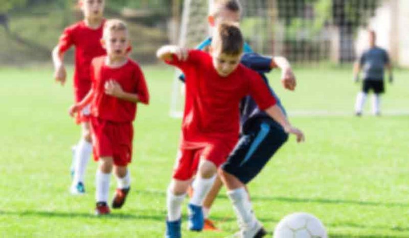 Barn spelar fotboll.