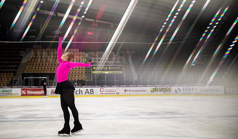 Tjej klädd i rosa som utövar konståkning i ishall