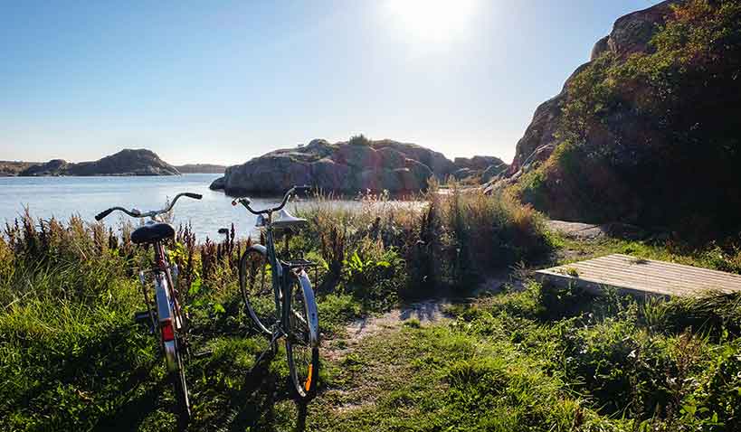 Solen skiner på två cyklar som står parkerade vid havet