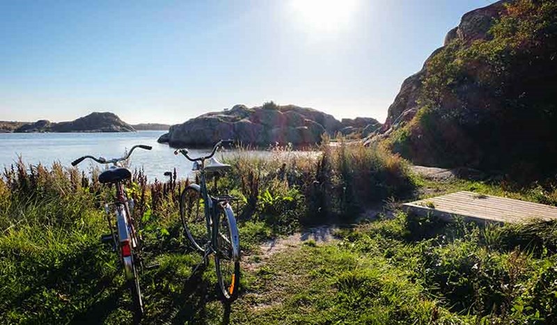 Solen skiner på två cyklar som står parkerade vid havet