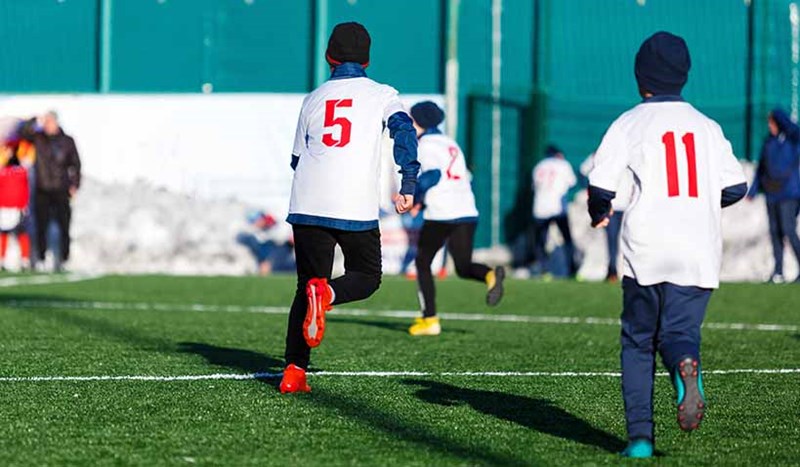 Fotbollsspelare med mössor under vintertid på gräsplan