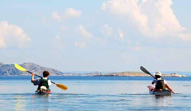 Två personer paddlar kajak i skärgården