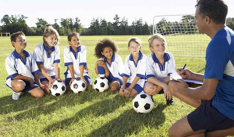 Fotbollsträning med juniorlag och deras tränare på gräsplan