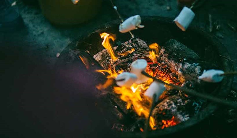 Marshmallows som grillas på pinne utomhus över öppen eld