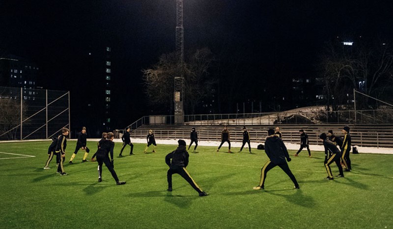 Ett gäng träningssugna som värmer upp på en upplyst fotbollsplan