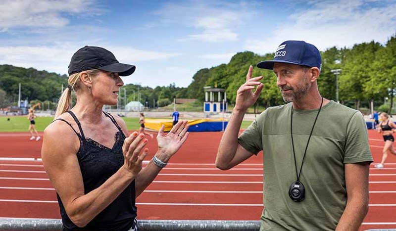 Erica Johansson samtalar med Yannic Tregaro på en friidrottsarena