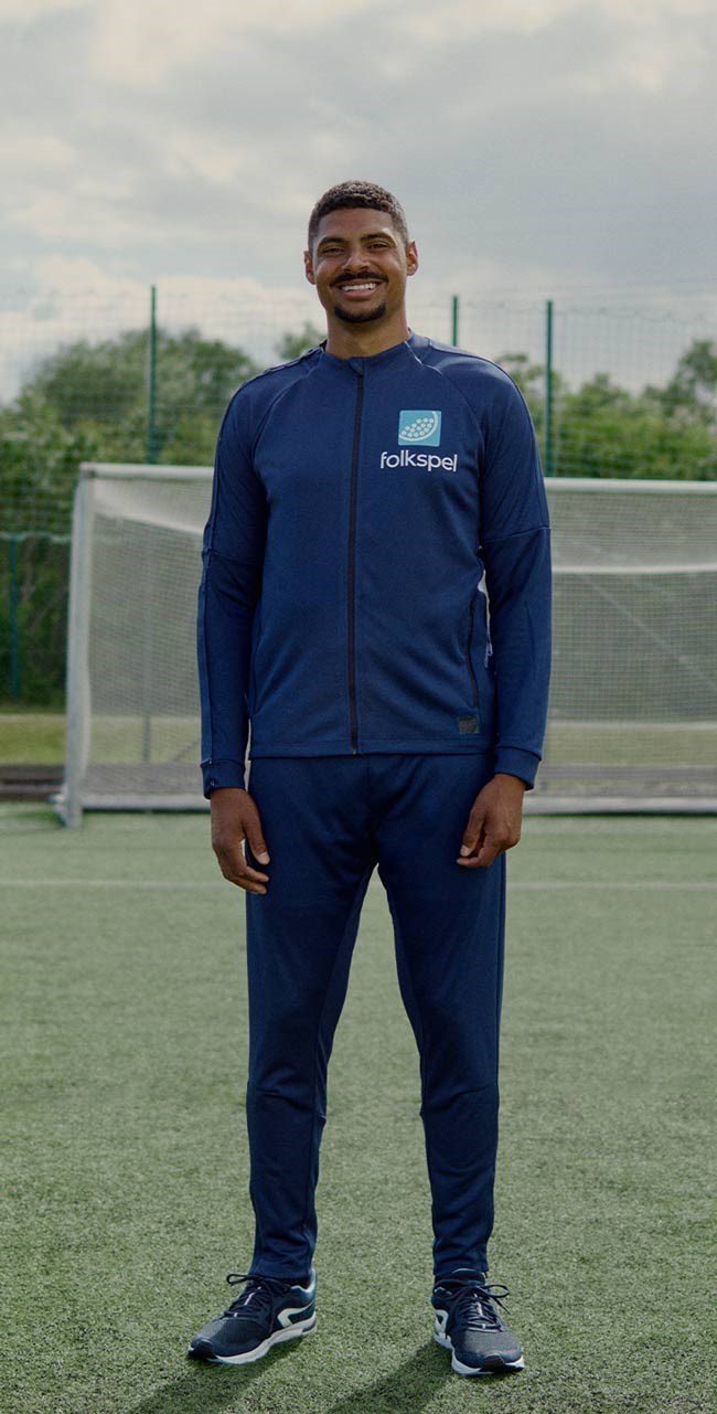 Michel Tornéus står framför ett fotbollsmål iklädd träningskläder från Folkspel